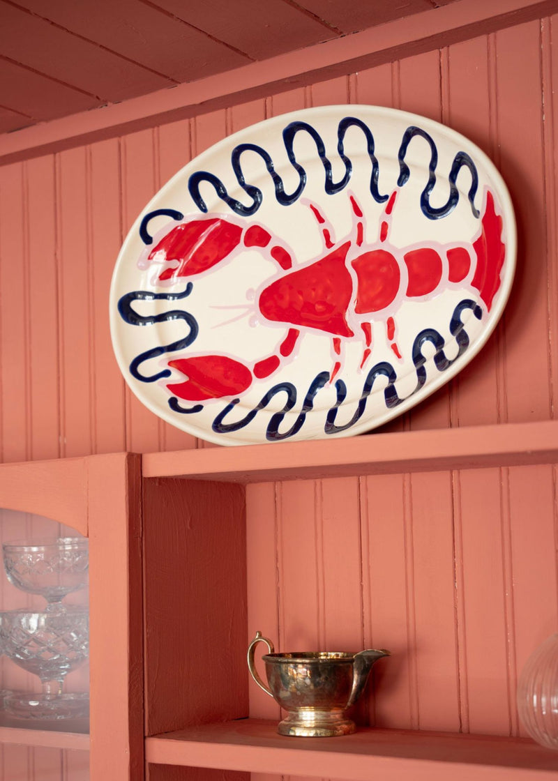 Pink cabinet with lobster ceramic plate on dsiplay by Amuse La Bouche